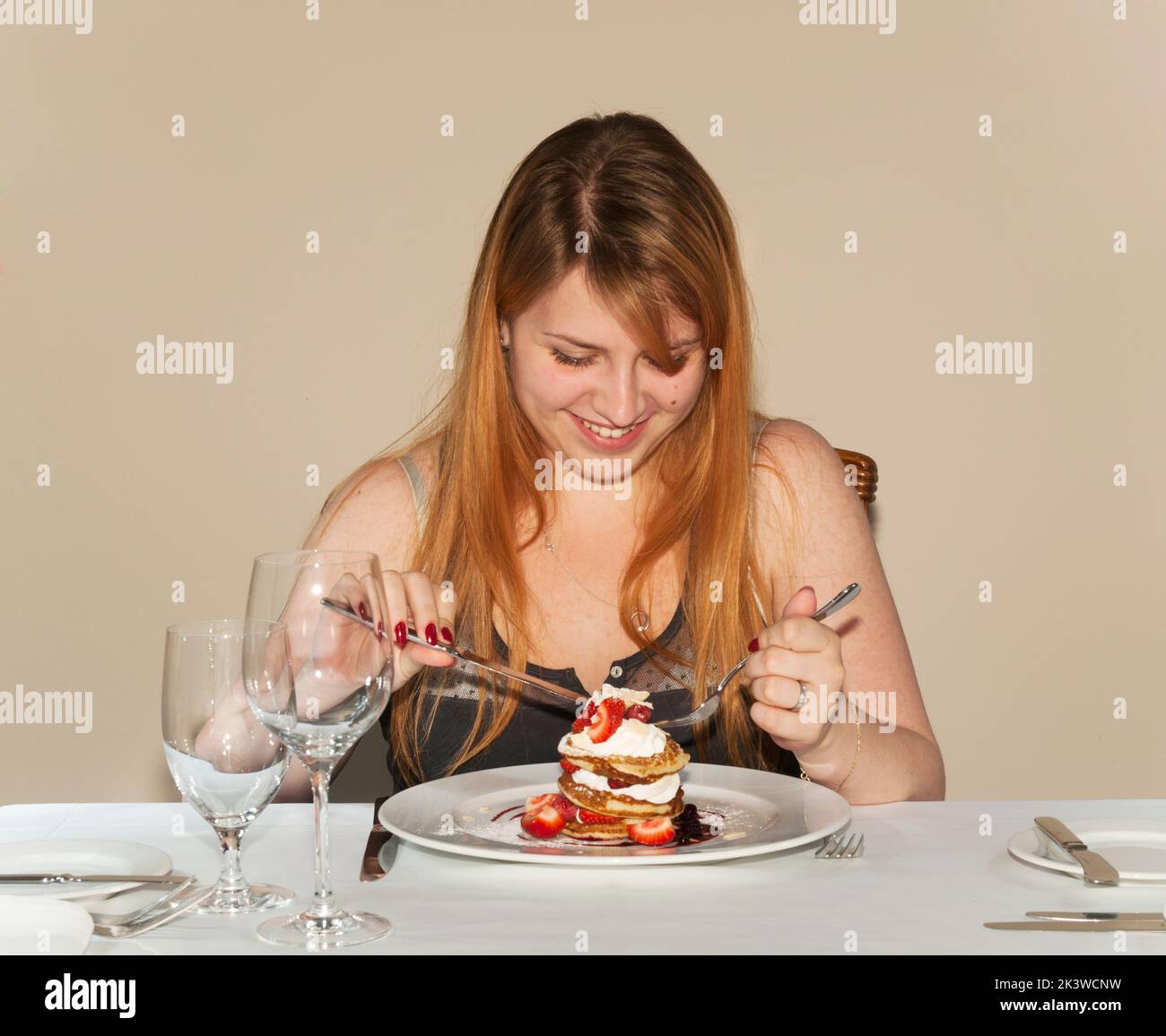 Young lady eating raspberry pancake Stock Photo
