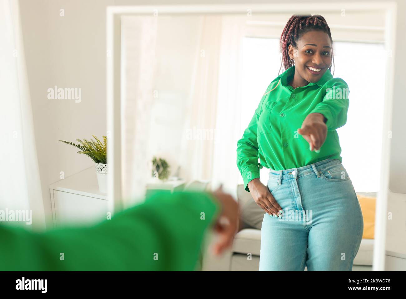 Self confident black woman pointing finger at her reflection in mirror, dancing and felling good, enjoying good mood Stock Photo