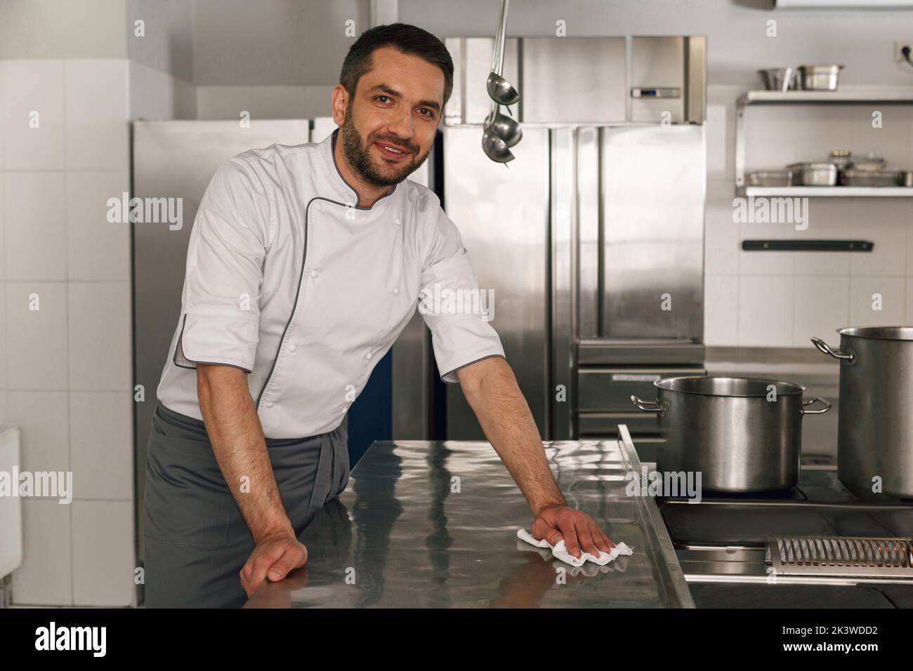 Young handsome male chef cleaning his workplace on kitchen in restaurant Stock Photo