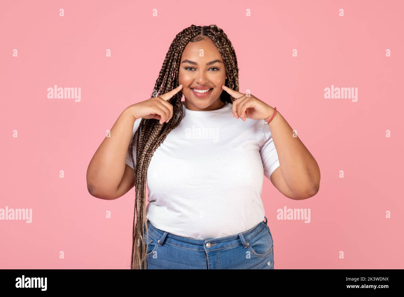 Cheerful Black Oversized Lady Posing Touching Cheeks Over Pink Background Stock Photo