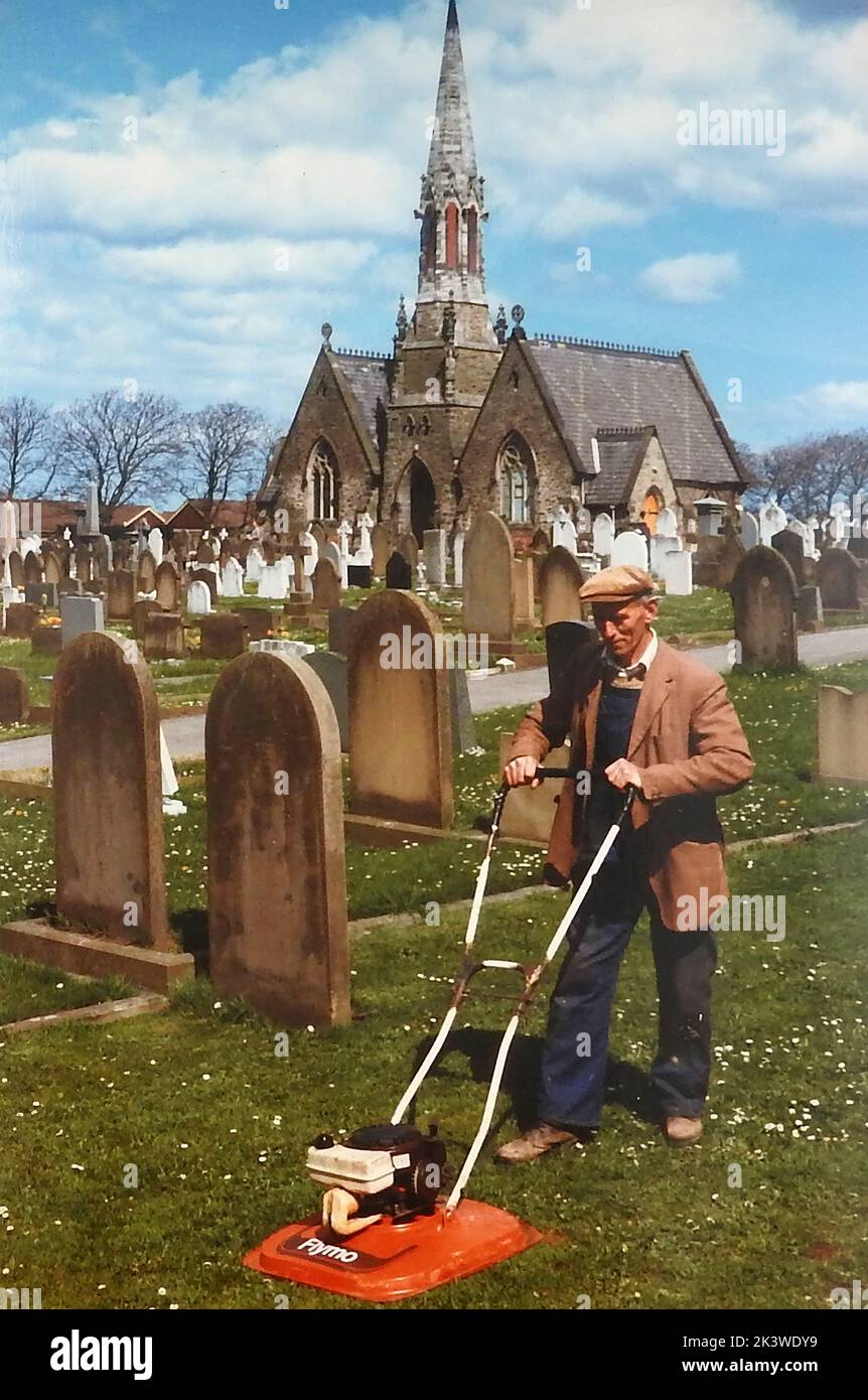 A 1986 photograph of the sexton of Larpool Lane Cemetery, Whitby, Yorkshire, mowing grass around the gravestones Stock Photo