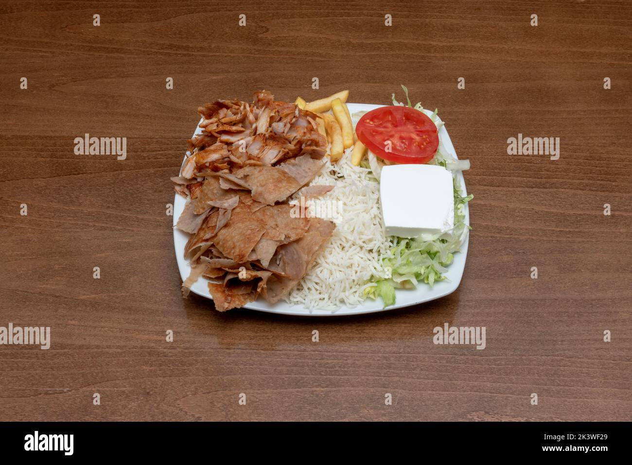 Typical combo plate of pakistani restaurants in europe with lamb and chicken kebab roll meat with french fries, white rice, feta cheese and salad Stock Photo