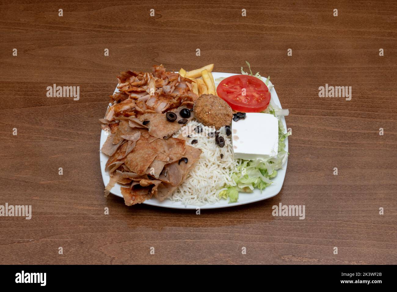 Typical mixed plate of Pakistani restaurants in Europe with lamb and chicken kebab meat, falafel medallion, black olives with French fries, white rice Stock Photo