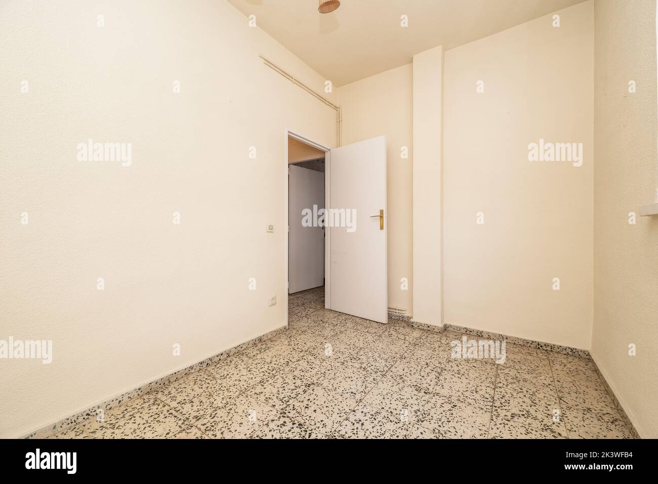 Empty room terrazzo flooring, cream painted walls and simple white wooden door Stock Photo