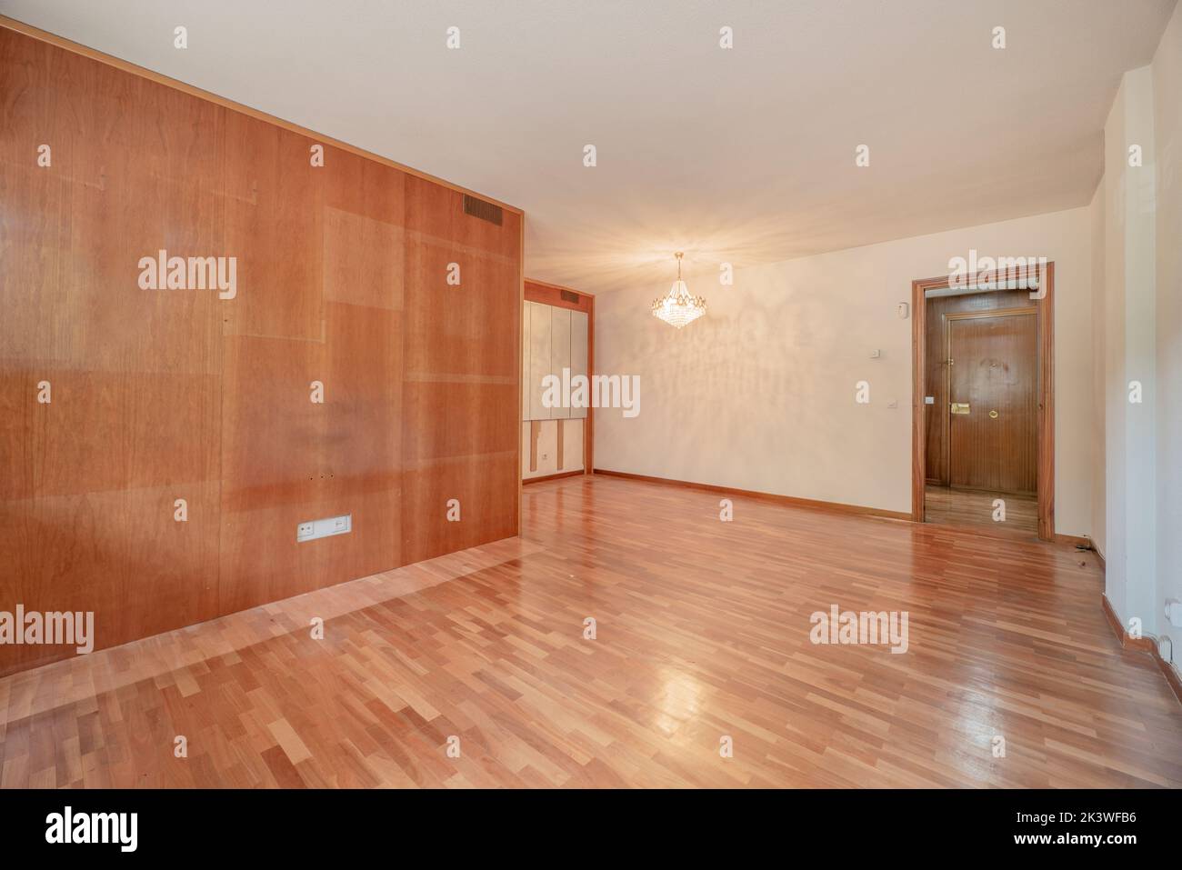 Empty room with a wall covered with a wooden varnish mural in a color that matches the parquet floors Stock Photo