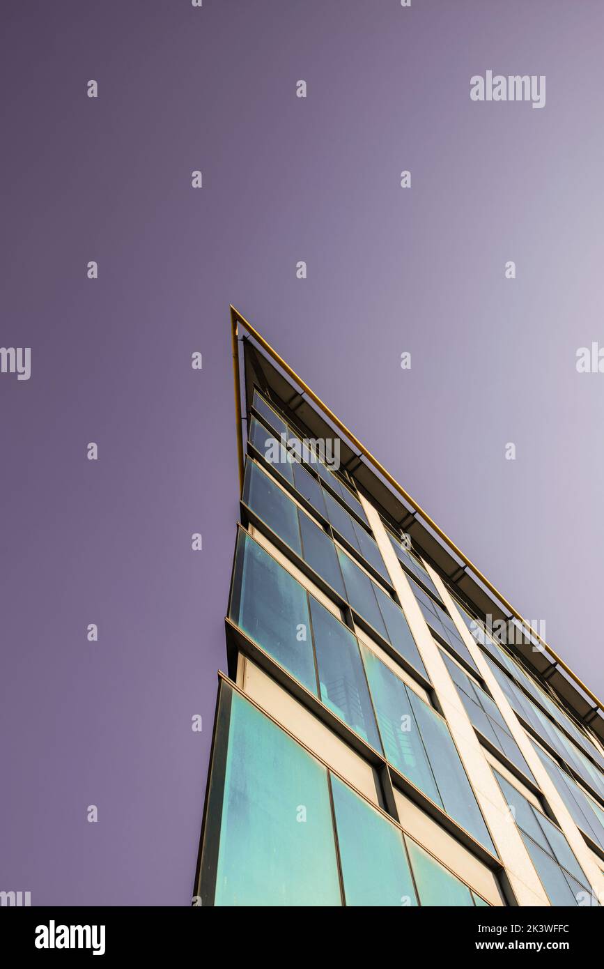 Vertex of a facade of a building with glass cover and a purple sky Stock Photo
