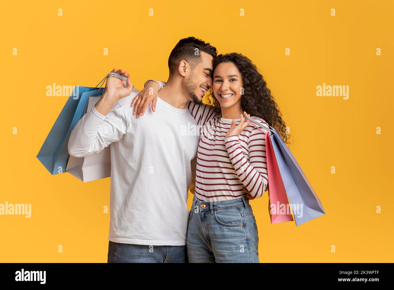 Romantic Young Arab Couple Holding Shopping Bags And Embracing Stock Photo