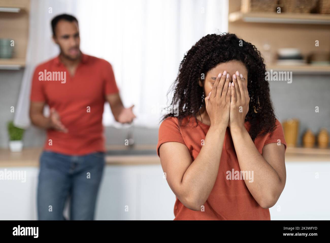 Sad angry millennial black male scolding to crying offended female in kitchen interior, free space Stock Photo