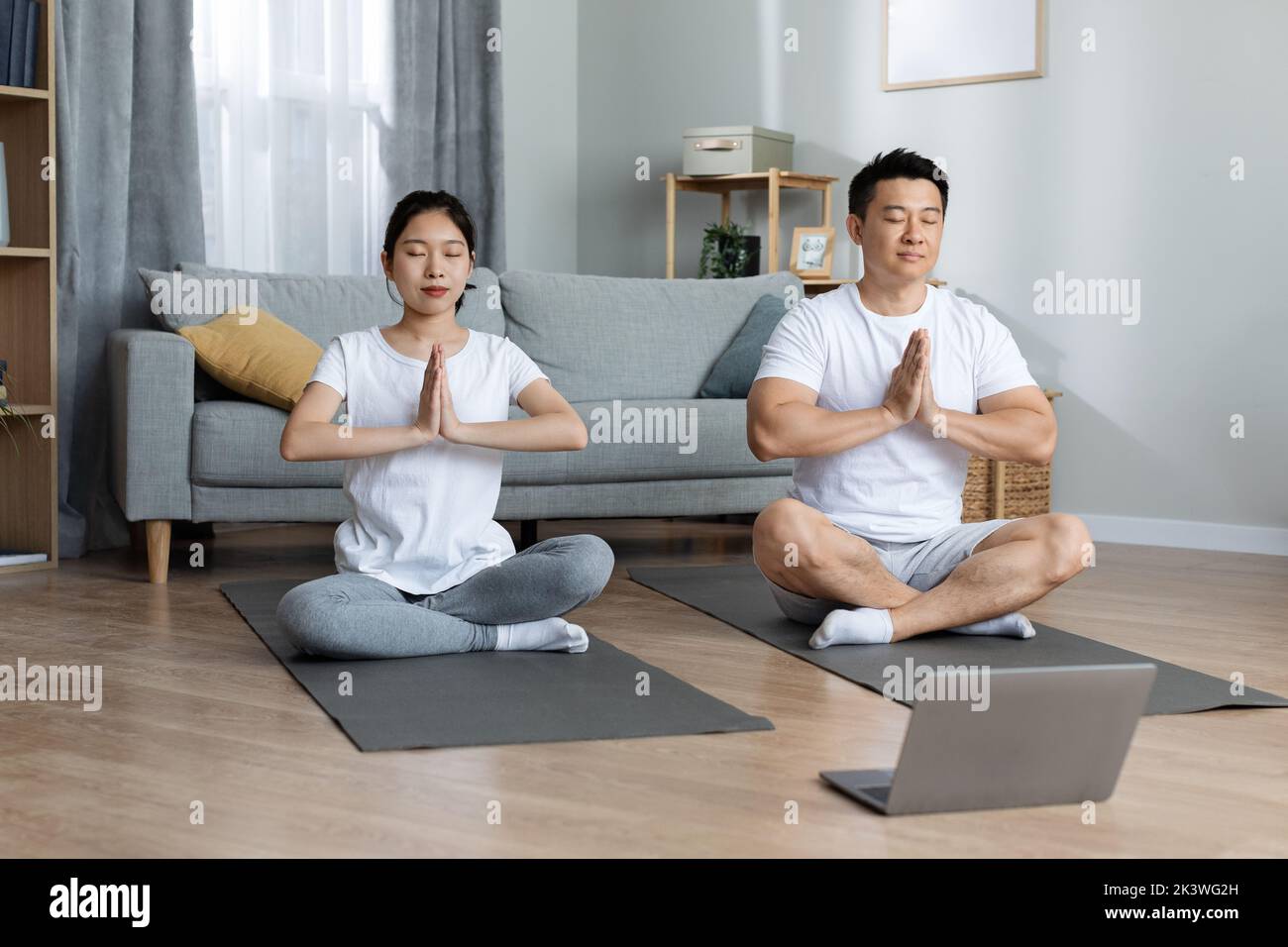 Relaxed korean couple meditating together at home Stock Photo