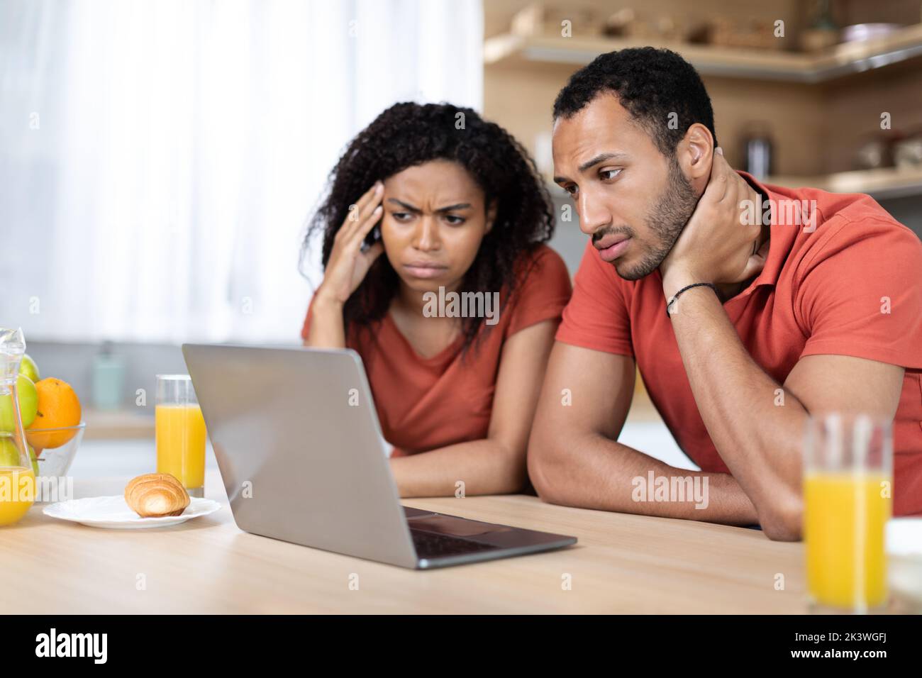 Upset millennial black wife and husband have video call, look at laptop in minimalist kitchen interior Stock Photo