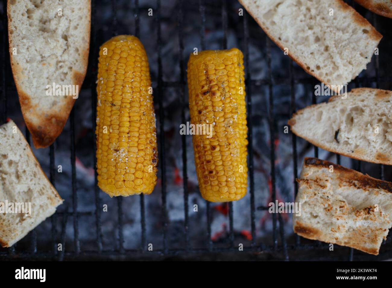 Corn cobs put on the barbecue with bread on a summer holiday outside the house. Stock Photo