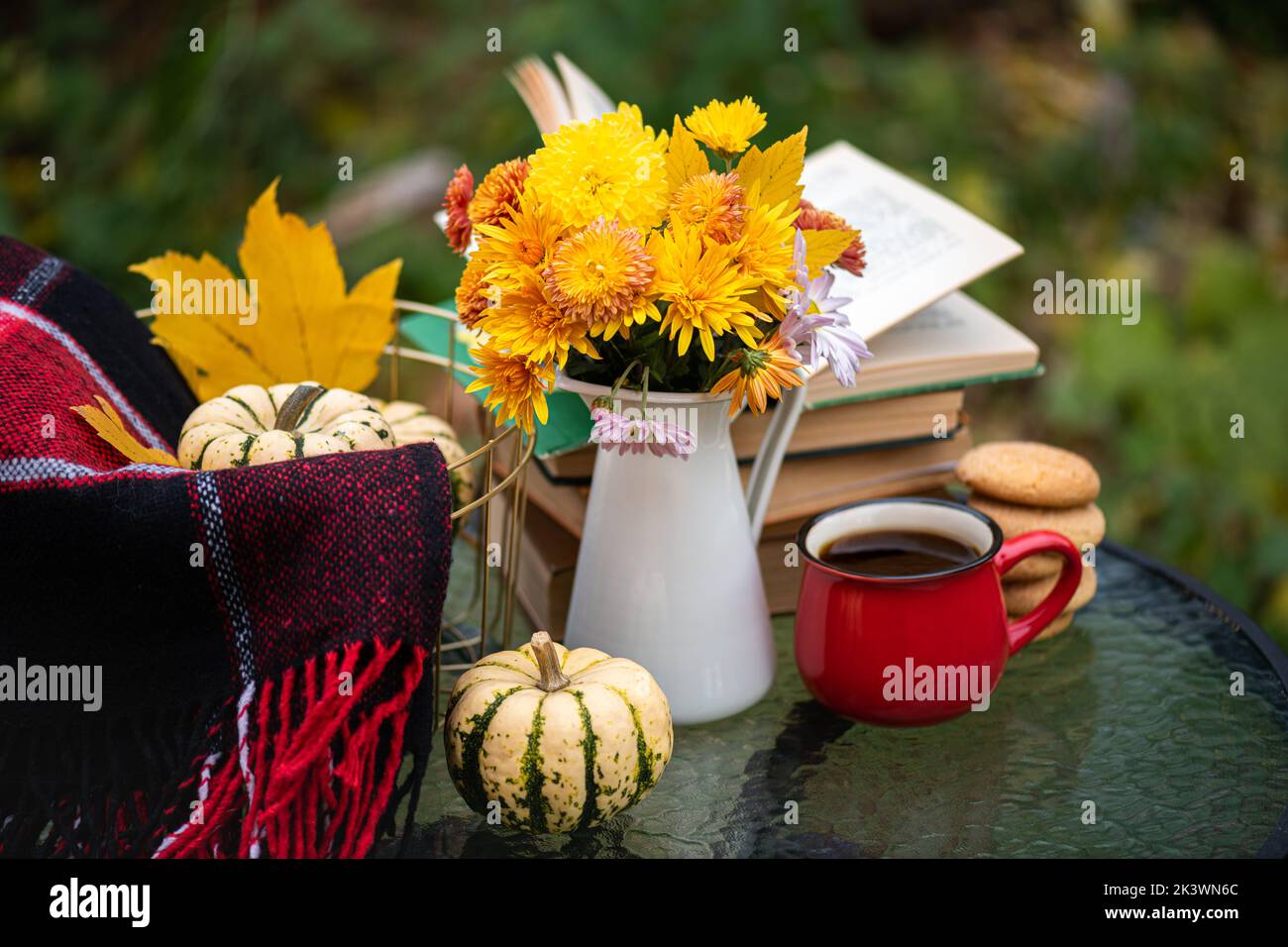Bouquet of flowers, pumpkin, coffee cup, books on table in autumn garden. Rest in garden, reading books, breakfast, cozy in nature concept. Autumn tim Stock Photo