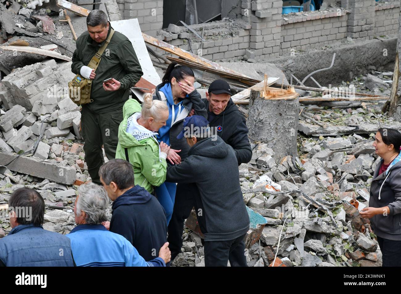 Relatives and friends comfort a woman after rescue workers found a body of a person under the debris following a Russian attack that heavily damaged a high school in Mykolaivka. Dmitry Peskov, press secretary of the Russian President, has stated that Russia will continue the war even after sham referendums are conducted, and it will aim to occupy the entire territory of Donetsk Oblast. Stock Photo