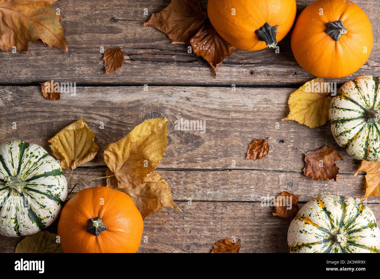 Autumn background with pumpkins and autumn leaves on rustic wooden background. Concept of Thanksgiving day or Halloween. Flat lay autumn composition w Stock Photo