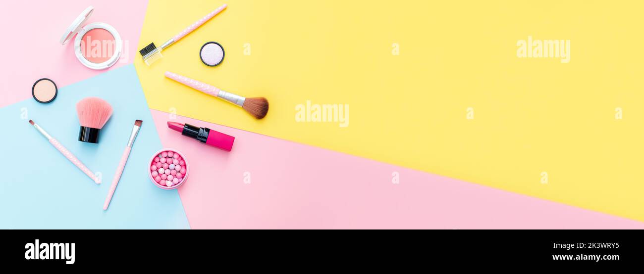 Makeup products and decorative cosmetics on color background flat lay. Fashion and beauty blogging concept. Long web format for banner Stock Photo