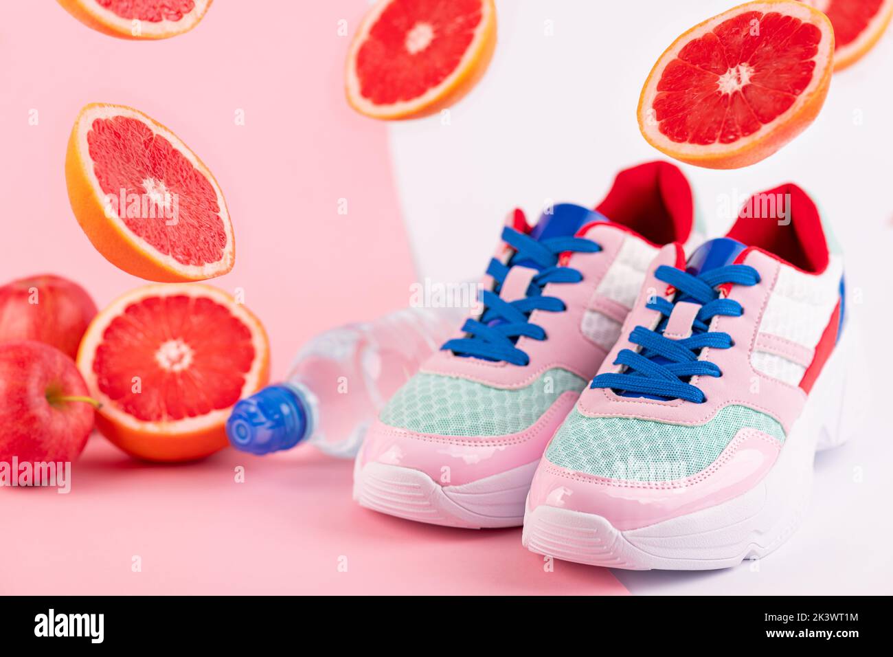 Sport equipment sport shoes, bottle of water, citrus fruits grapefruits on pink and white background. Healthy lifestyle, fitness, diet, slimming conce Stock Photo