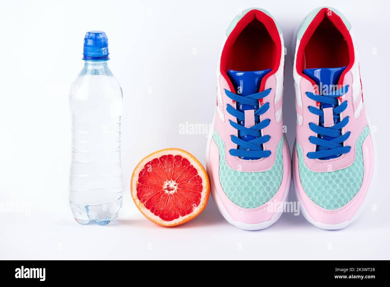 Female sport accessories sport shoes, bottle of water, citrus fruits on white background. Healthy lifestyle, fitness, diet, slimming concept. Trendy s Stock Photo
