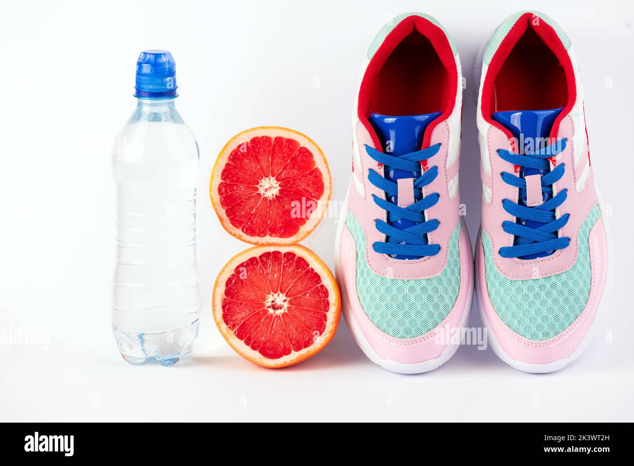 Female sport accessories sport shoes, bottle of water, citrus fruits on white background. Healthy lifestyle, fitness, diet, slimming concept. Trendy s Stock Photo