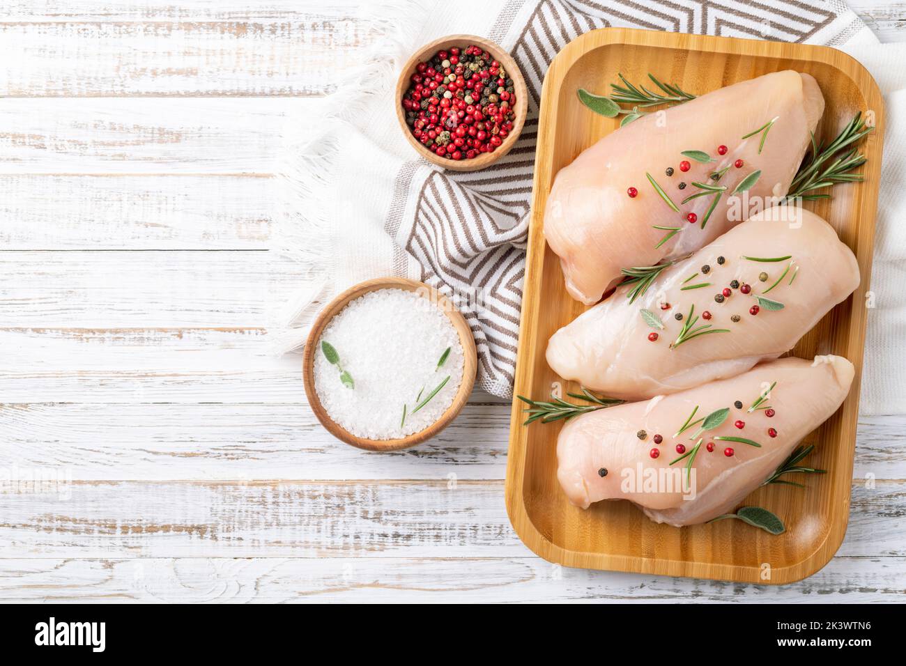 Chicken fillet with herbs and spices on white wooden table flat lay. Chicken meat with ingredients for cooking. Top view, copy space Stock Photo