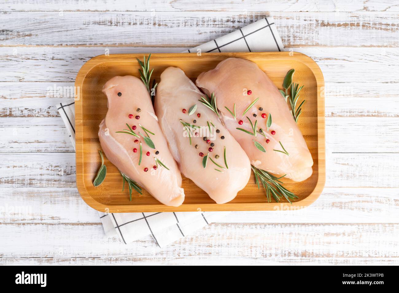 Raw uncooked chicken breasts with spices and herbs on white wooden background, meat with ingredients for cooking. Top view Stock Photo