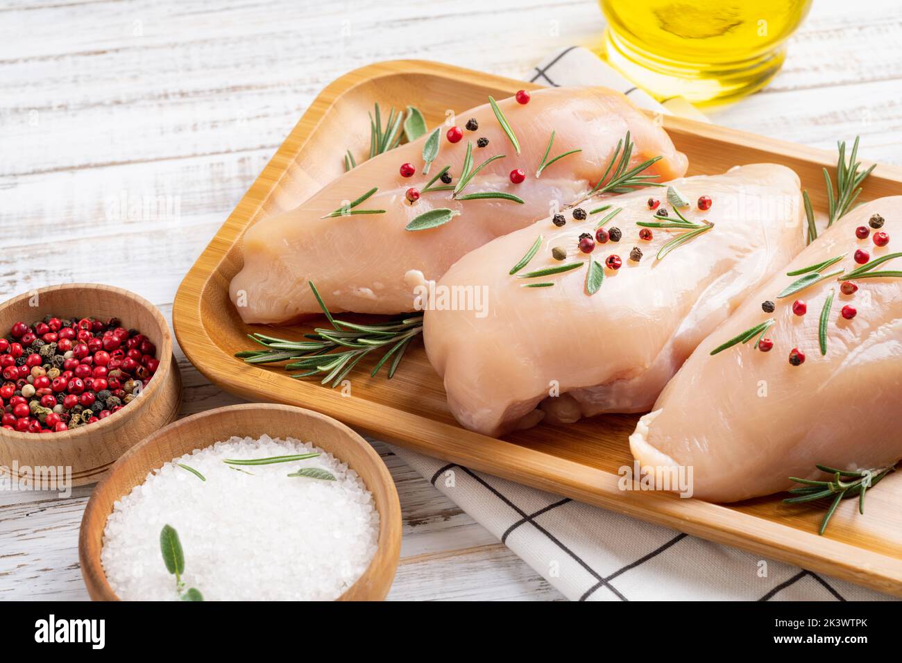 Raw uncooked chicken breasts with spices and herbs on white wooden background, chicken meat with ingredients for cooking Stock Photo