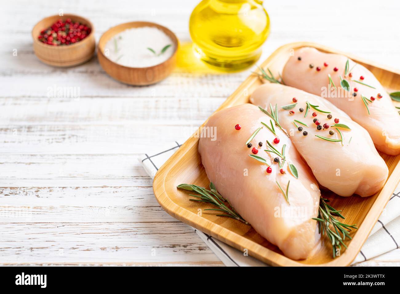 Chicken fillet with herbs and spices on white wooden table close up. Chicken meat with ingredients for cooking. Copy space Stock Photo