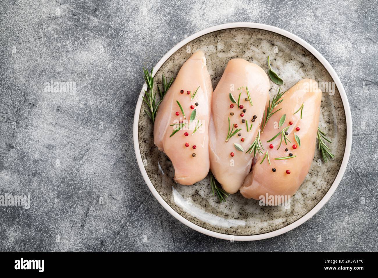 Chicken fillet with herbs and spices on gray table flat lay. Chicken meat with ingredients for cooking. Copy space Stock Photo