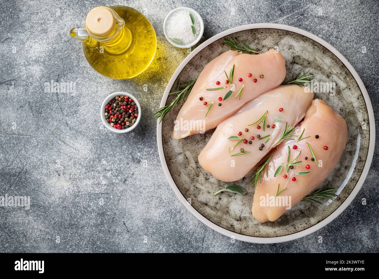 Raw meat of chicken breasts for healthy food diet on grey concrete background. Chicken meat with ingredients for cooking. Healthy food. Copy space Stock Photo