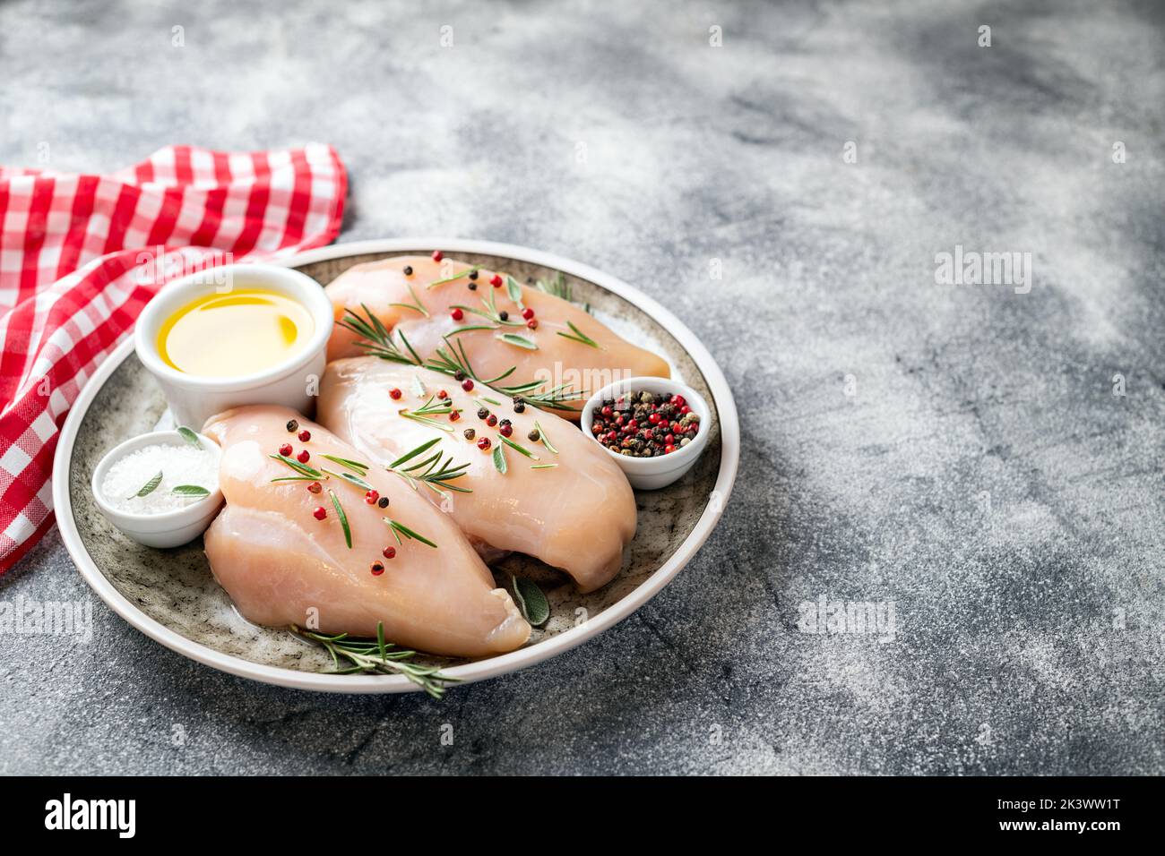 Chicken fillet with herbs and spices on gray table close up. Chicken meat with ingredients for cooking. Copy space Stock Photo