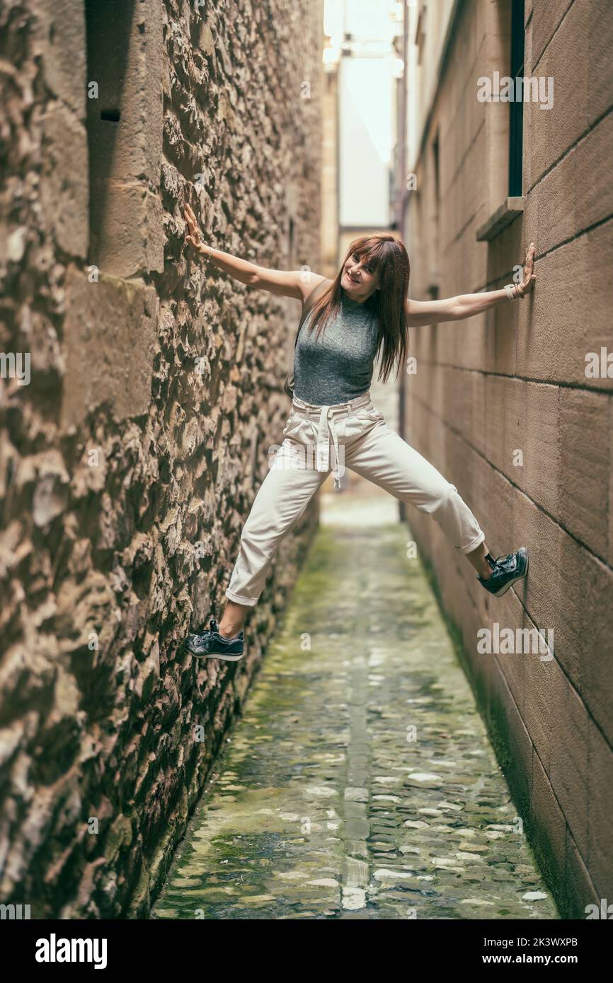 woman having fun climbing up between the walls of two buildings Stock ...