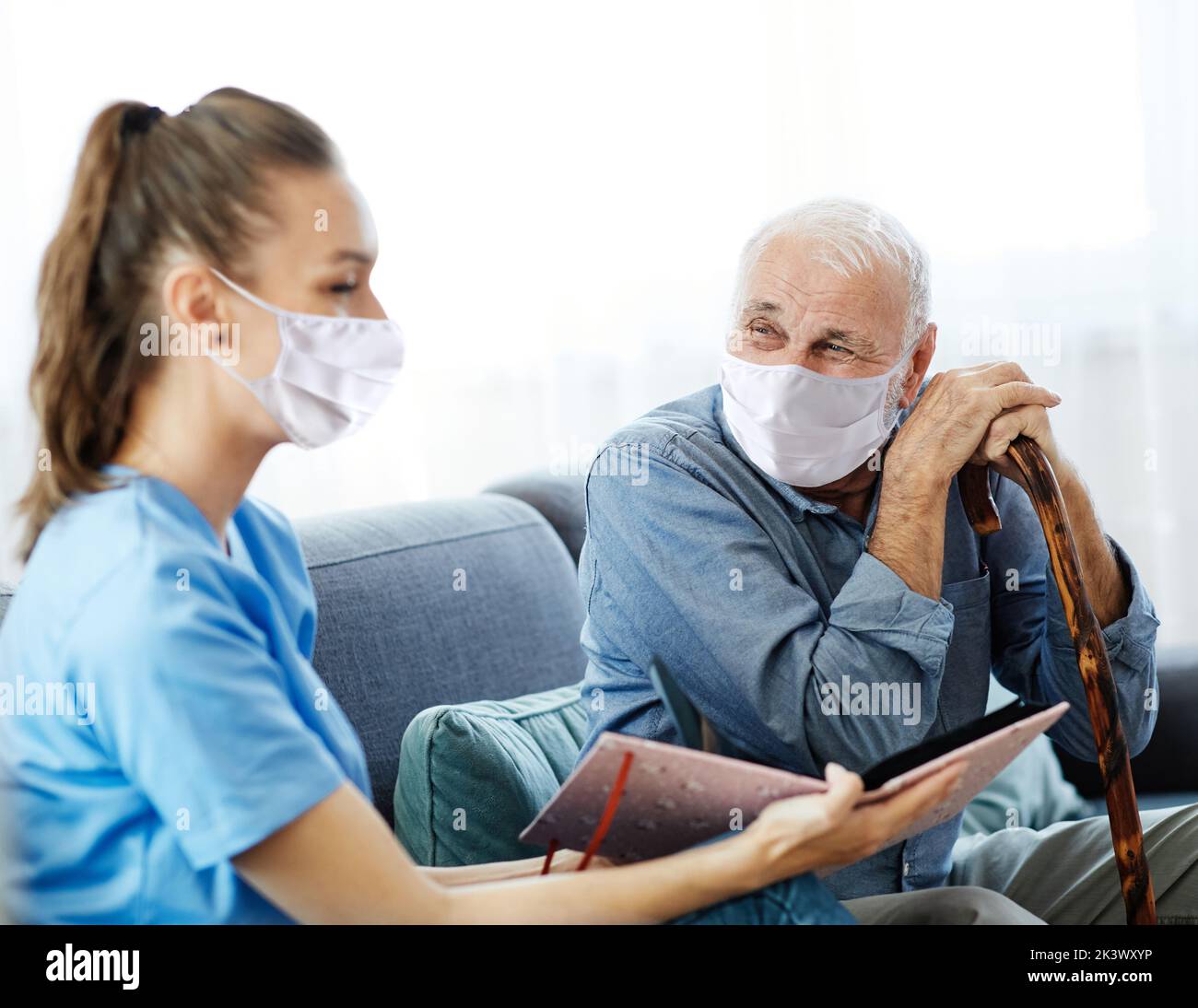 Doctor or nurse caregiver with senior man wearing protective masks