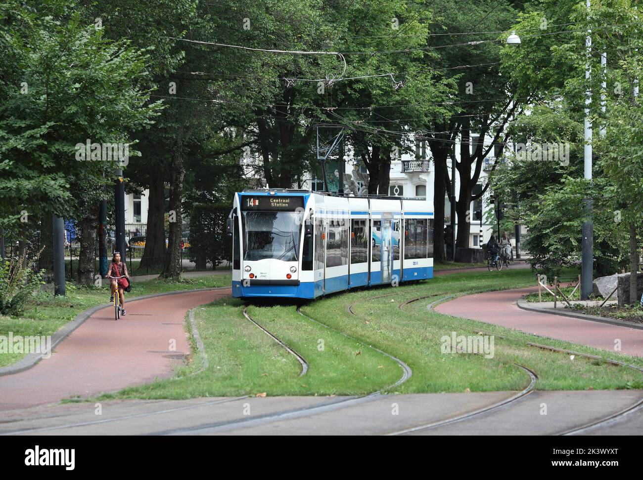 A tram on Plantage Middenlaan, Amsterdam.  A street for sustainable transport: tram lines flanked by cycle lanes, and footpaths for pedestrians. Stock Photo