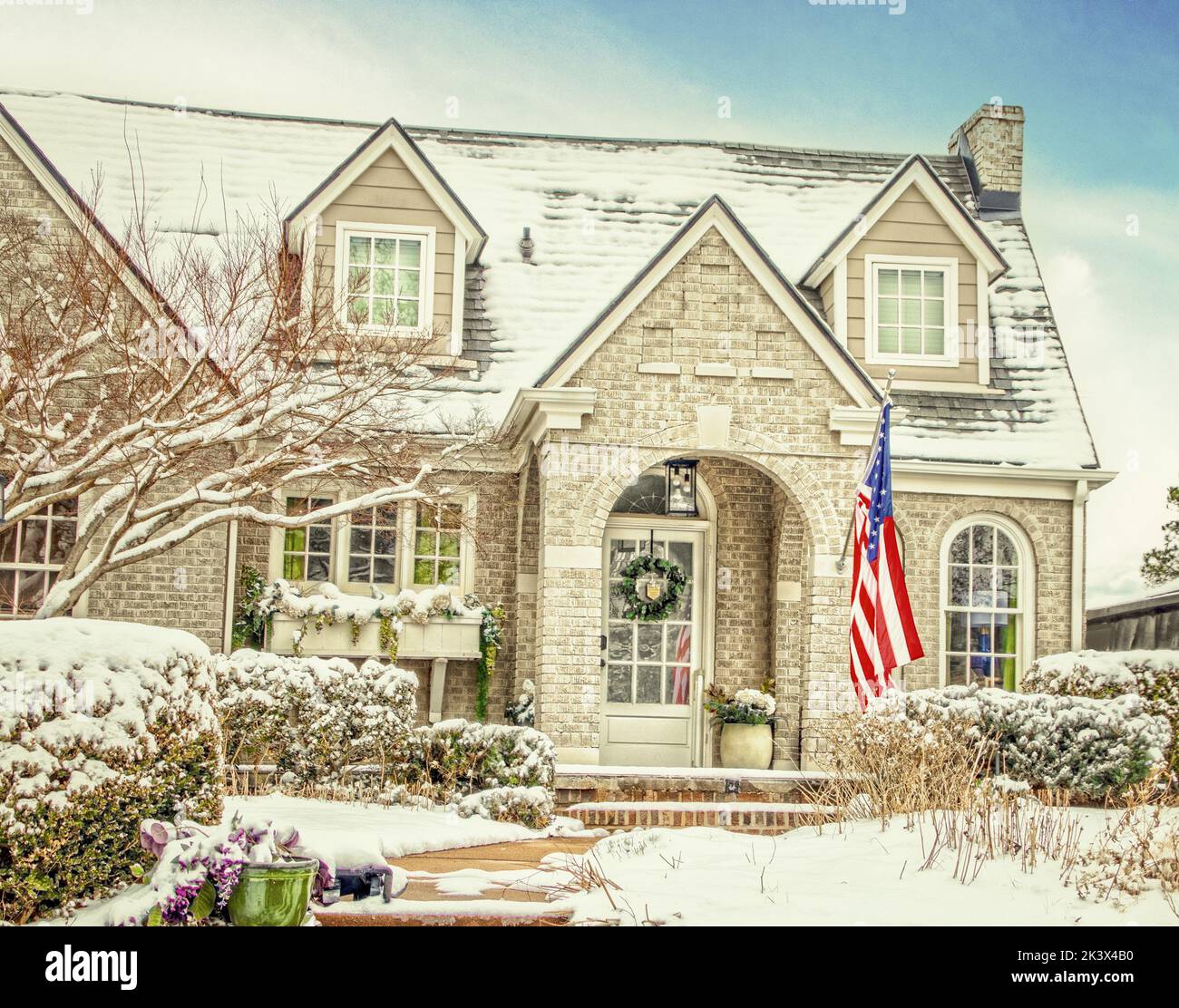 Wintery Snowy light brick house with dormers and arches and a window