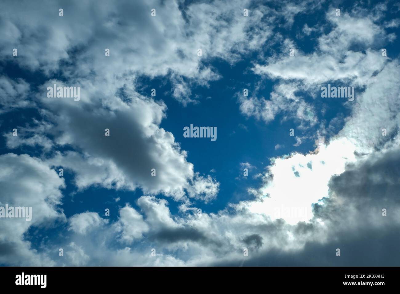 Blue sky with thunderclouds. The sun breaks through the clouds. Black clouds. Stock Photo