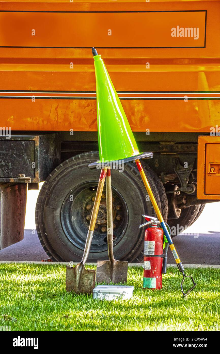 Tools of the trade - Tree cutters - shovels and rake and fire extinguisher and green safety cone set up in silly pyramid by orange work truck Stock Photo