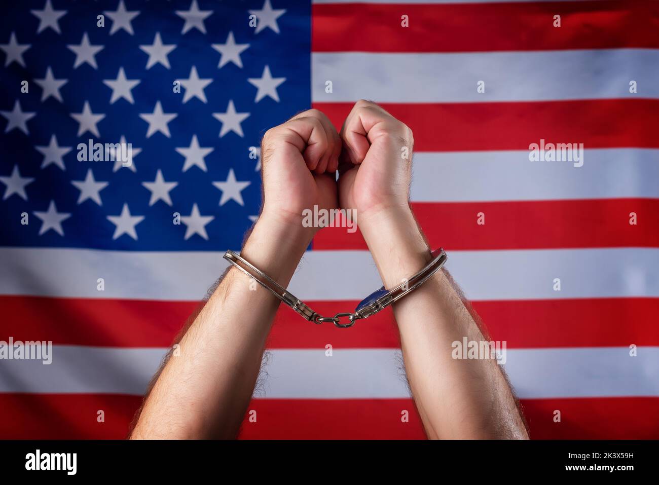 Handcuffed hands with the U.S. flag in the background. Condemned by the American financial system. Social and economic crisis Stock Photo