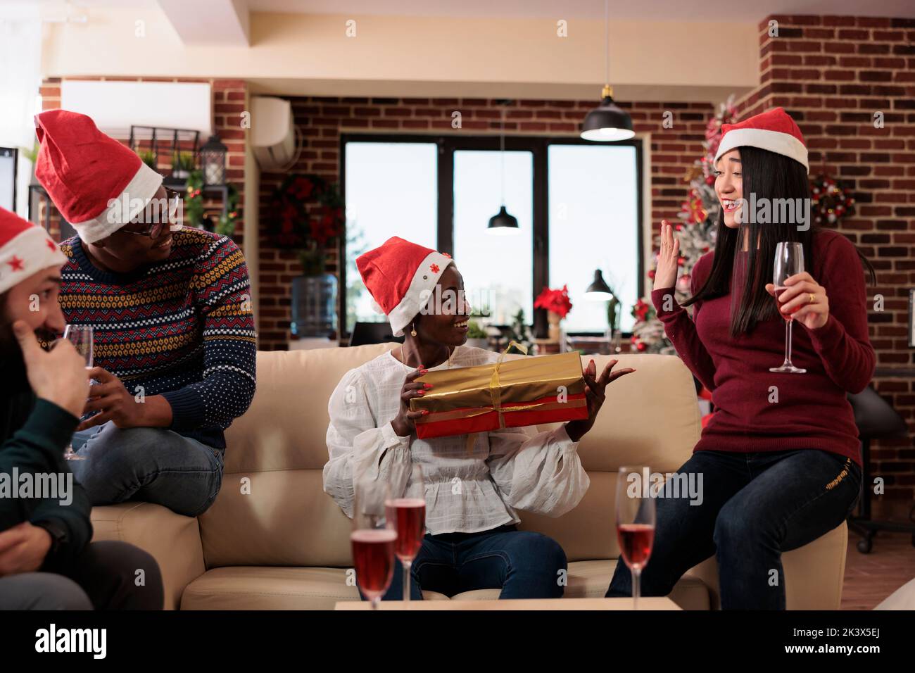 Multiethnic team of coworkers exchanging presents at christmas office party, celebrating xmas festivity with alcohol and gifts. Having fun with surprise at holiday celebration. Stock Photo