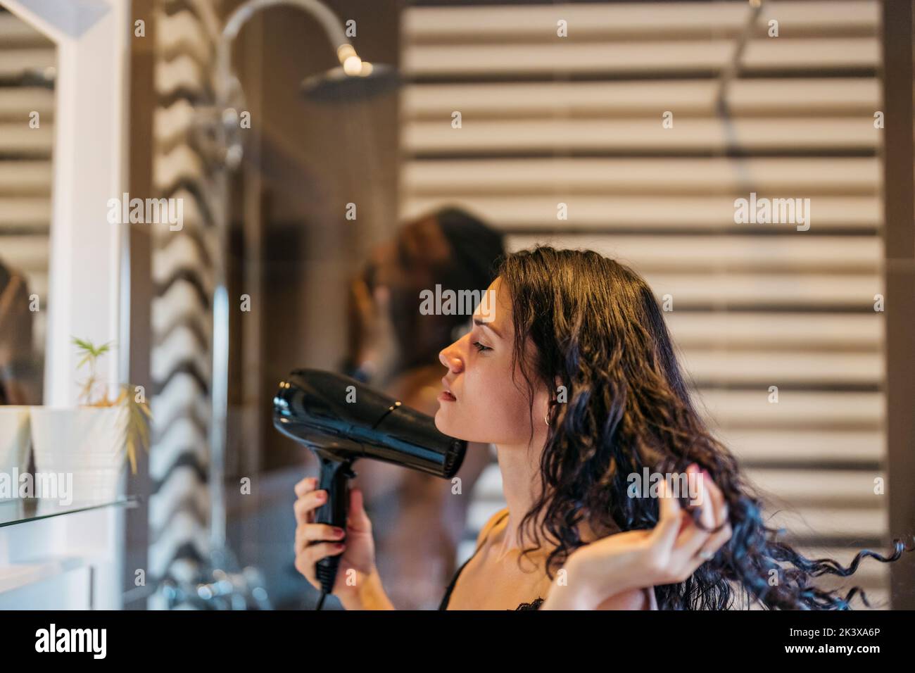 young Latin girl drying her hair with a hairdryer while her boyfriend ...