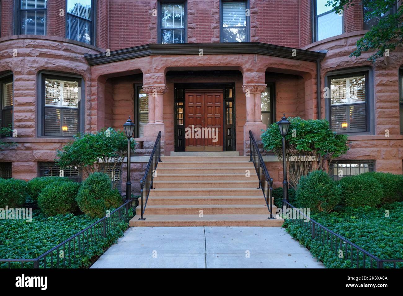 Front steps of old brownstone style apartment building with large porch Stock Photo