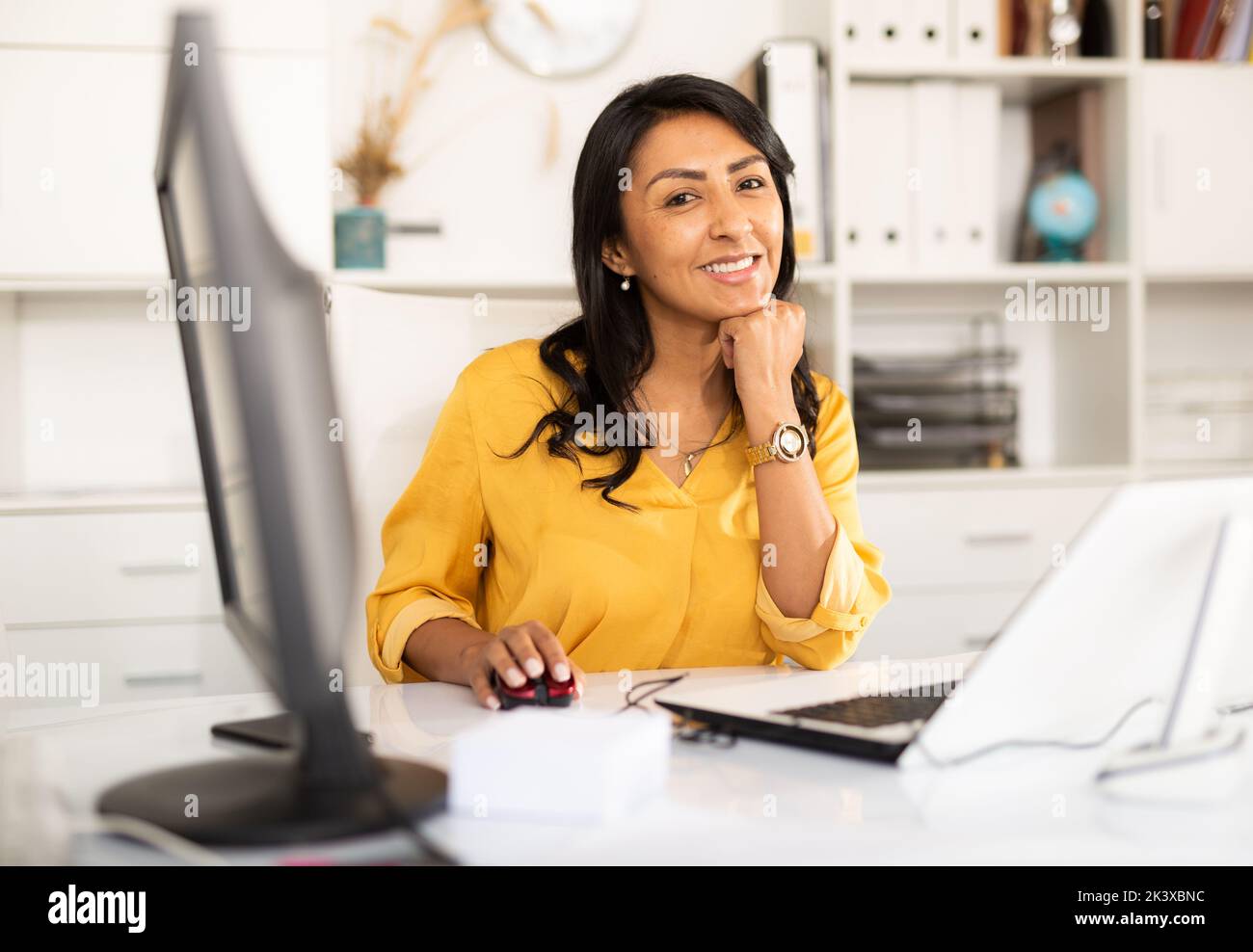 Smiling latin american female office employee working on computer Stock ...