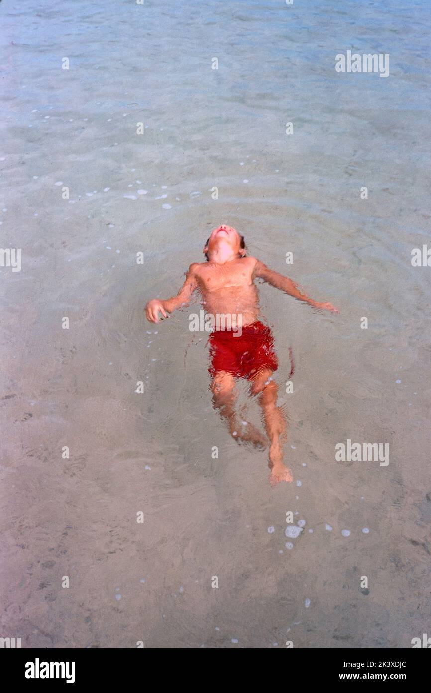 High Angle View of Young Boy floating on his back in Water, Bermuda, Toni Frissell Collection, 1956 Stock Photo