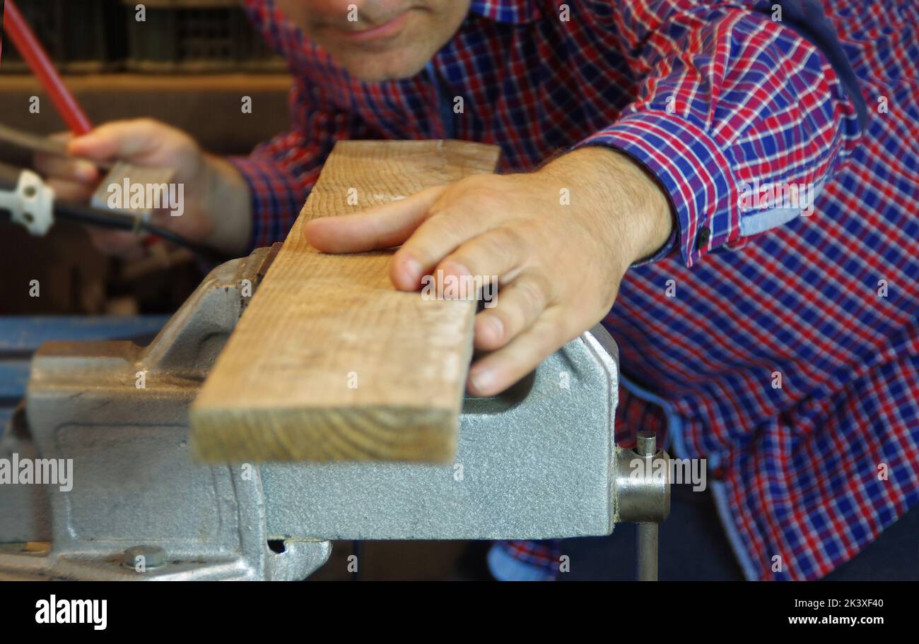 Carpenter in the workshop prepares a cutting raw board. Joiner worker in carpentry shop. A thorough expert and careful craftsman focused on work. Stock Photo