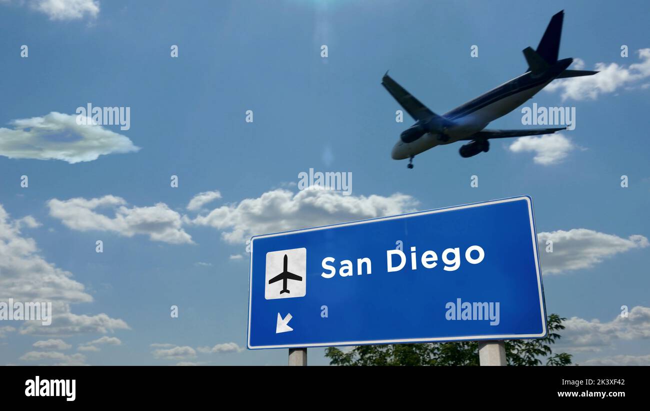 Airplane silhouette landing in San Diego, California, USA. City arrival with international airport direction signboard and blue sky. Travel, trip and Stock Photo