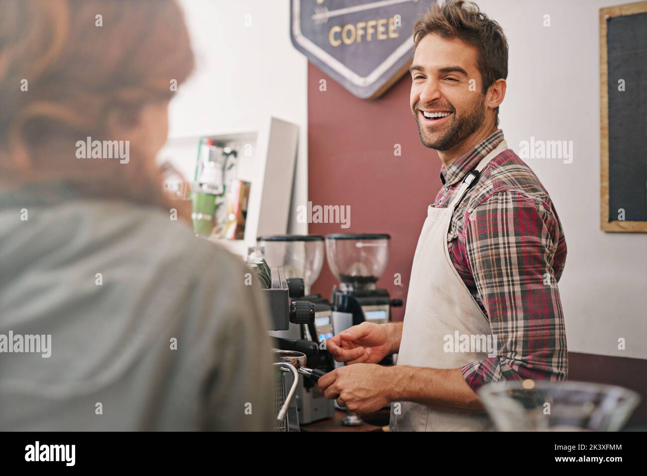 Casual conversation with a customer. a young male barista serving a customer. Stock Photo