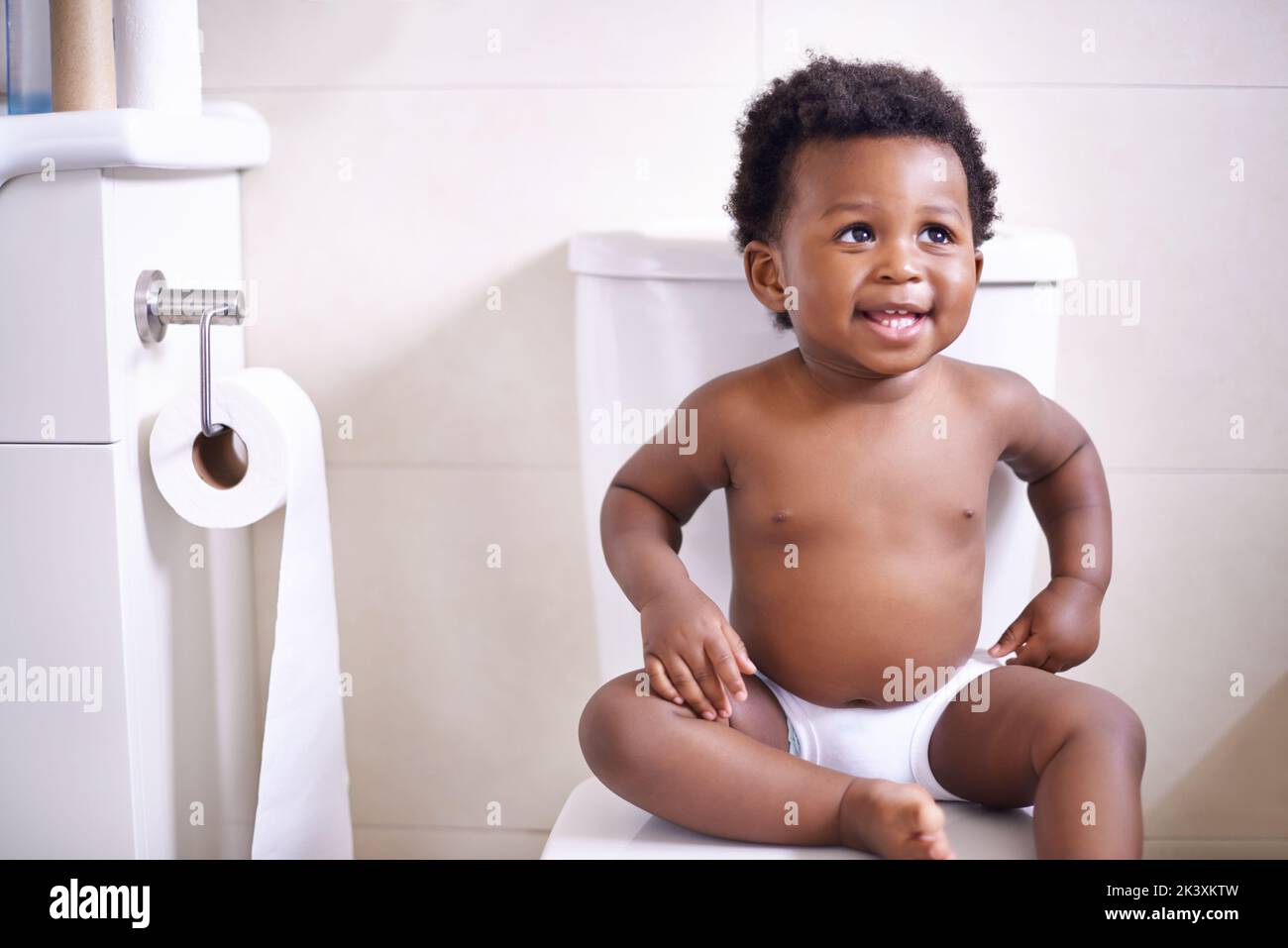 Im gonna ace this potty training thing. an adorable baby boy sitting on the toilet in the bathroom. Stock Photo