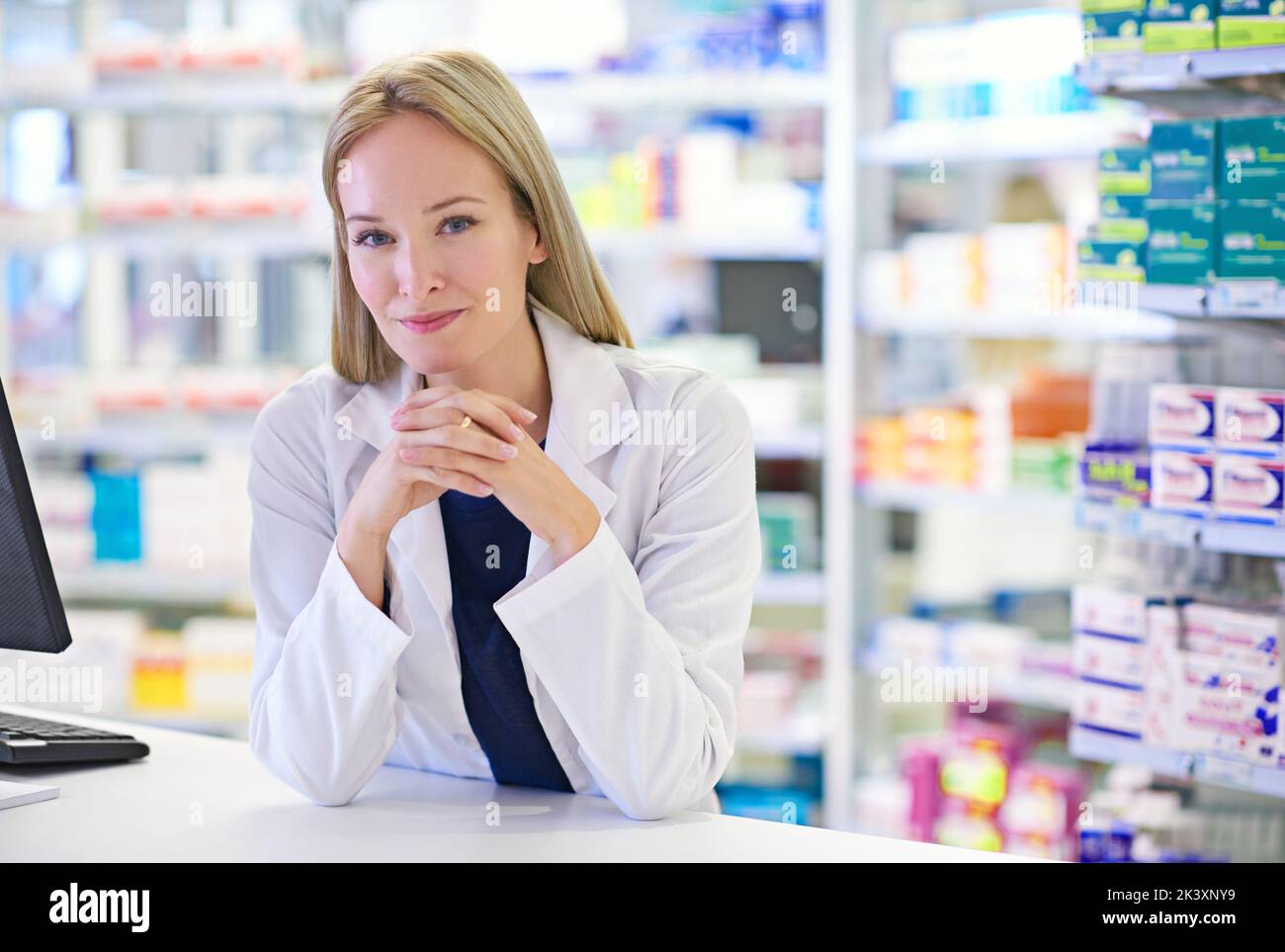 Always ready to assist. Portrait of an attractive pharmacist standing at the prescription counter. Stock Photo