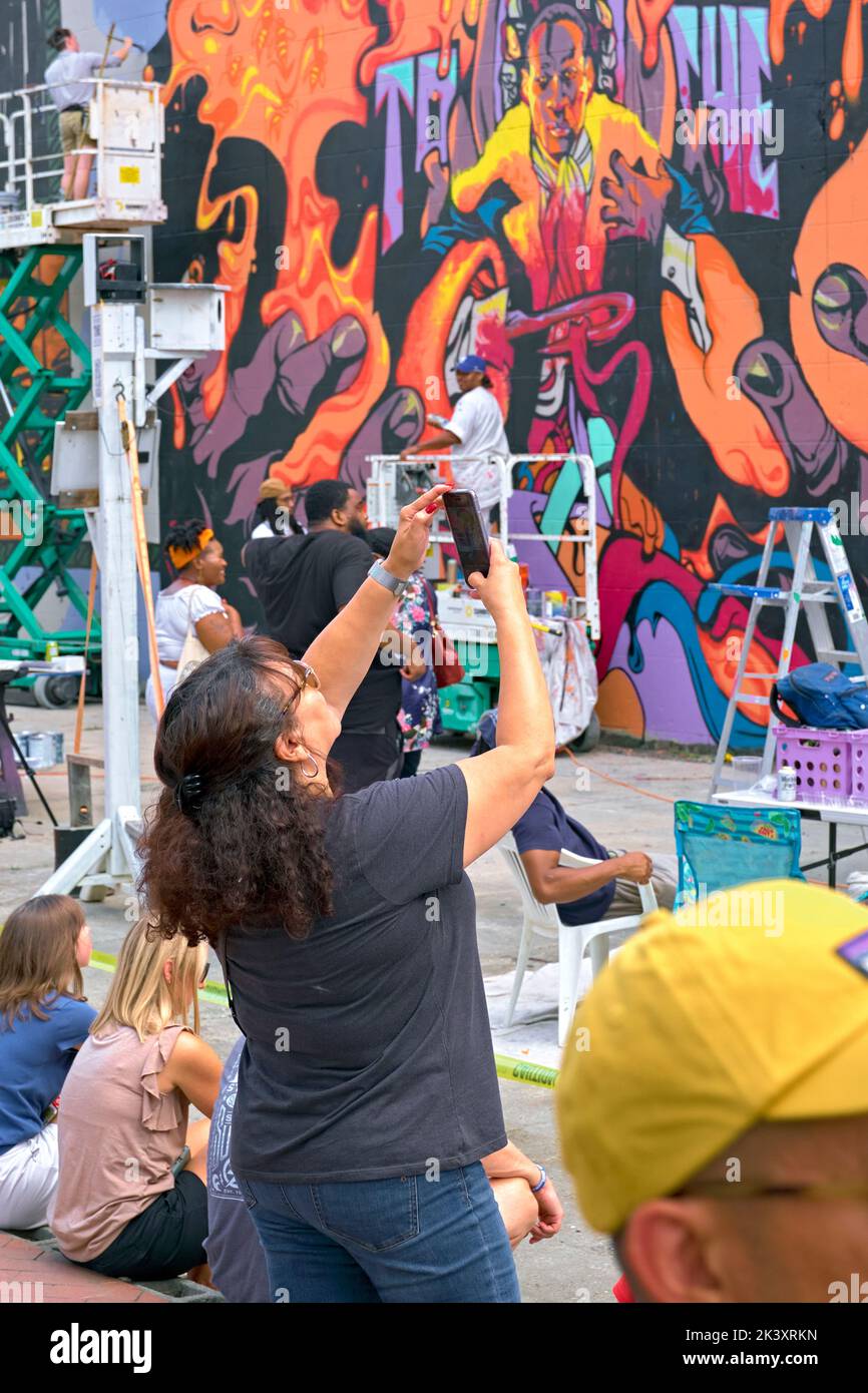 Visitors watch the creation of new murals at the RVA Street Art Festival at the Power Plant along Richmond VA's Canal Walk. Stock Photo
