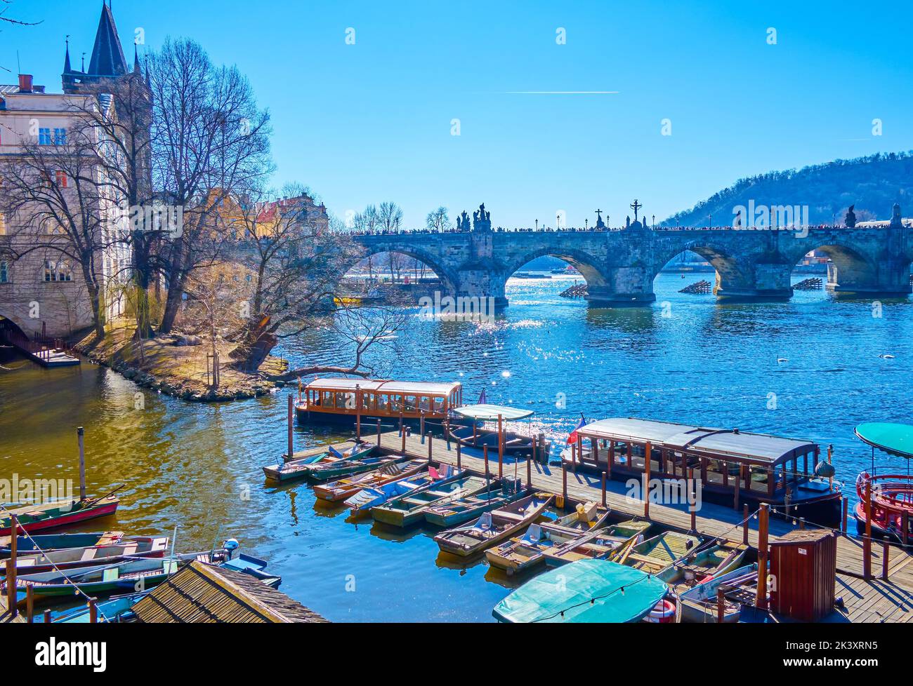 The small pier with old wooden boats on Vltava river in Stare Mesto District with a view on Charles Bridge in Prague, Czech Republic Stock Photo