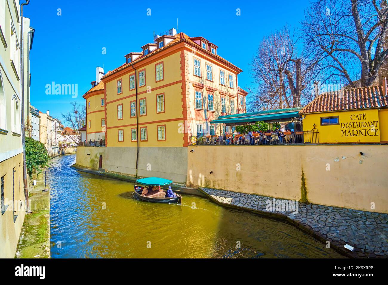 PRAGUE, CZECH REPUBLIC - MARCH 12, 2022: Small boat sails along Certovka Canal among medieval mansions and popular restaurants, on March 12 in Prague, Stock Photo