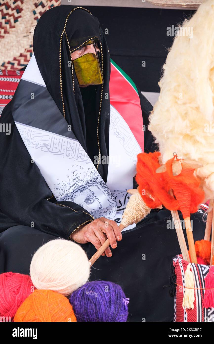 Masked Arab Woman from Abu Dhabi Wearing an Abaya, Putting Wool on to a Spindle. Stock Photo